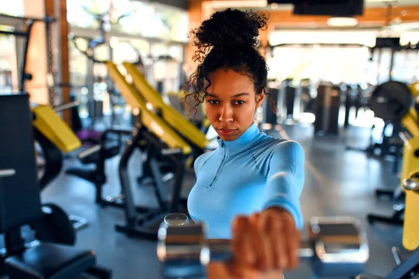 Afroameričanka Sportovním Oblečení Cvičí Činkami Tělocvičně Pozadí Sportovního Vybavení Aktivní — Stock fotografie