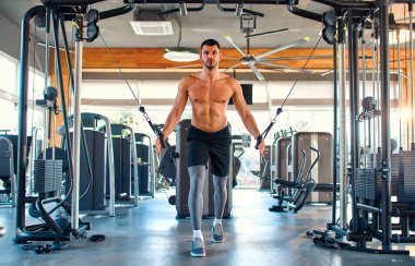 Caucasian muscular man in sportswear is training with trx suspension in the gym. The concept of sports and recreation.