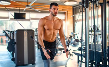 Caucasian muscular man in sportswear is training with trx suspension in the gym. The concept of sports and recreation.