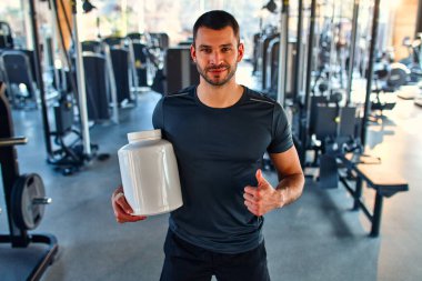 Spor salonunda besin takviyesi ya da protein alan genç yakışıklı bir adam. Spor ve eğlence konsepti. Spor beslenmesi.