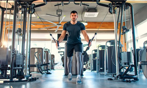 Spor giyimli beyaz kaslı adam spor salonunda trx süspansiyonlu antrenman yapıyor. Spor ve eğlence kavramı..