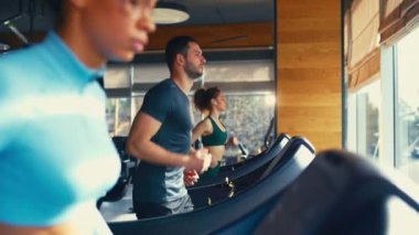 Spor salonunda koşu bandında koşan etnik çeşitliliğe sahip bir grup genç. Kardiyo çalışması. Spor ve eğlence kavramı..