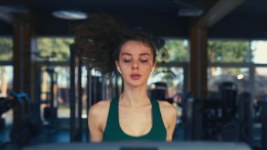 Spor giyimli ince bir kız spor salonunda koşu bandında kardiyo çalışması yapıyor. Çalışan aktivite Spor ve eğlence kavramı..