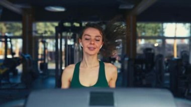 Spor giyimli ince bir kız spor salonunda koşu bandında kardiyo çalışması yapıyor. Çalışan aktivite Spor ve eğlence kavramı..