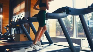 Spor giyimli ince bir kız spor salonunda koşu bandında kardiyo çalışması yapıyor. Çalışan aktivite Spor ve eğlence kavramı..