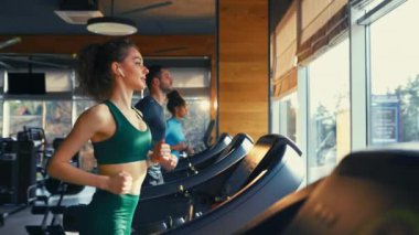 Spor salonunda koşu bandında koşan etnik çeşitliliğe sahip bir grup genç. Kardiyo çalışması. Spor ve eğlence kavramı..