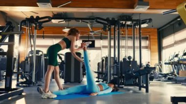 Spor giyimli Afro-Amerikan ve Kafkas kadınlar spor salonunda lastik paspaslar üzerinde esneme egzersizleri yapıyorlar. Spor ve eğlence kavramı..