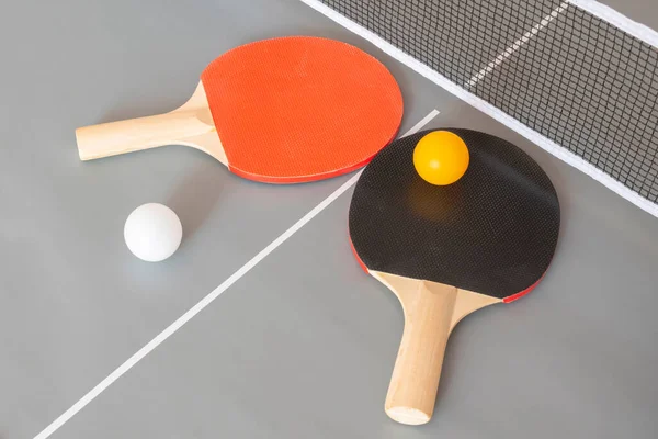 Two ping pong table tennis rackets and balls on a gray table