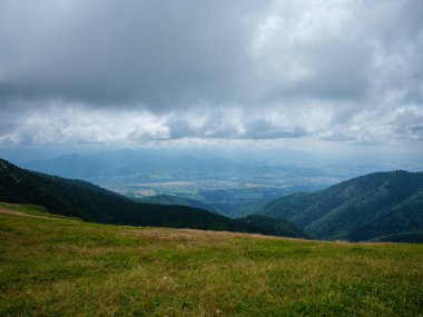 Slovenya Triglav Ulusal Parkı 'ndaki puslu dağların tepeleri. Kayalar ve yeşil çayırlar ile yaz manzarası.