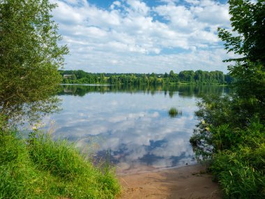 Kır ormanı gölü yazın koyu mavi sularda yansımalar ve kıyılarda yeşil ağaçlarla