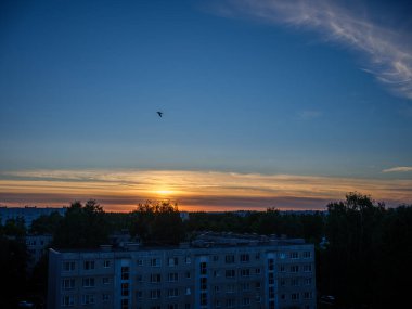 Şehrin çatıları üzerinde dramatik kırmızı ve koyu mavi bulutlar. Şehir silüeti.
