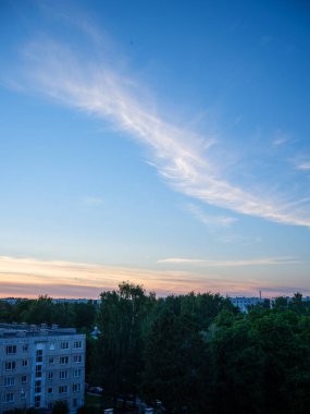 Şehrin çatıları üzerinde dramatik kırmızı ve koyu mavi bulutlar. Şehir silüeti.