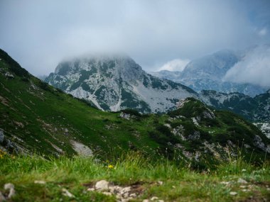 Güneşli yaz gününde alçak bulutlarla yürüyüş için kayalık dağ turizmi yolları