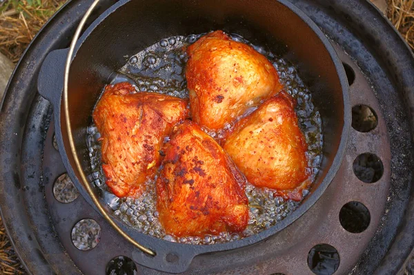 Tavuk butları dökme demir kazanda kızartılmış. Geri dönüşümlü bir arabanın kenarında pişirilmiş tavuk eti.. — Stok fotoğraf