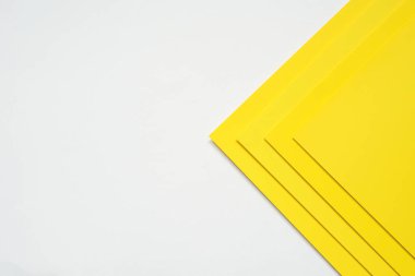 Sarı kağıtlar, tasarım elemanı veya web sitesi kapağı fikirleri olarak kullanılabilecek bu soyut arkaplan kavramında boş bir beyaz kağıdın üzerine istiflenmiştir..