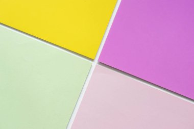 Blank light green paper, purple, yellow, and pink paper in geometric forms form an abstract background concept.