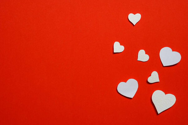 white paper cut into small hearts.  Paste on red paper, background concept for Valentine's .flat lay, copy space.