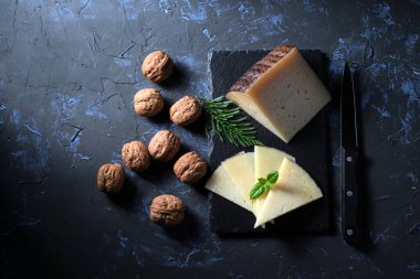 Tepeden gelen koyu arkaplanda ceviz ve kavrulmuş peynir dilimleri.