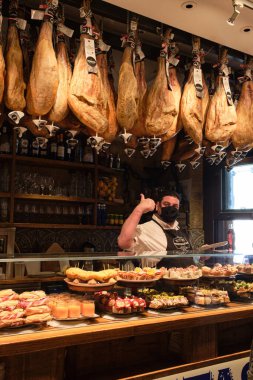 San Sebastian, İspanya; 27 Ekim 2021: Tipik pintxo bar ve Jabugo jambonu asma. Covid-19 salgınının son darbeleri, kurumların içinde işaretleri olan insanlar. Yeni gerçeklik.