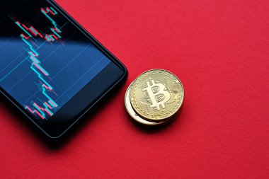 Şifreleme para birimlerinin kavramsal görüntüsü bitcoin ve akıllı telefon ile kırmızı arkaplan üzerinde grafik