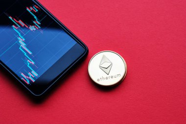Kripto para birimlerinin kavramsal görüntüsü ethereum ve kırmızı arkaplanda grafiği olan akıllı telefon