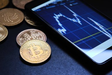 Akıllı telefon ve diğer altın kripto para birimleriyle birlikte bitcoin paralarının yakın plan görüntüsü.
