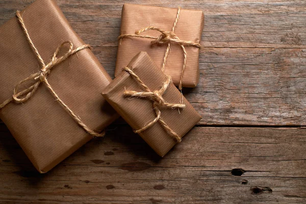 Kahverengi kraft kağıdına sarılı kutular ve kırsal ahşap masa üzerinde iple bağlanmış.