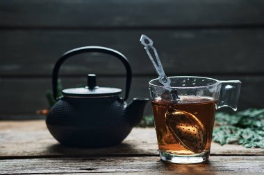 Cam bardakta kırmızı çay ve kırsal ahşap masada çaydanlık.