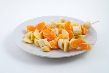 Beyaz arka planda muz, portakal ve elmadan oluşan meyve salatası