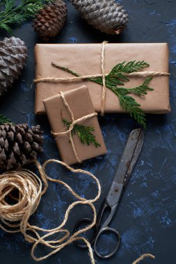 Kraft kağıdına sarılı Noel paketleri koyu desenli arka planda jütle bağlanmış.