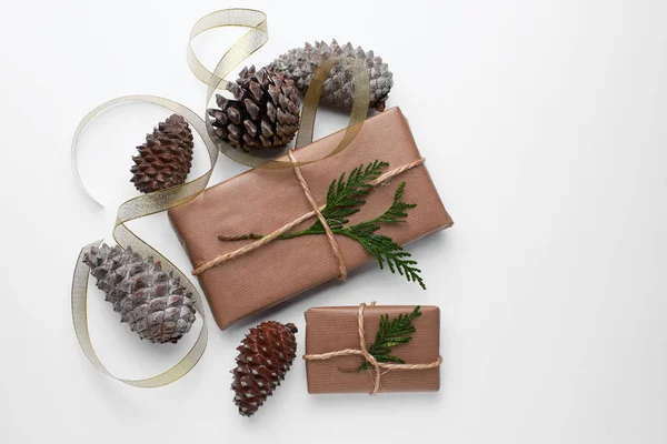 Background of christmas gift packages wrapped with craft paper and dried pine cones for decoration. Ecological concept