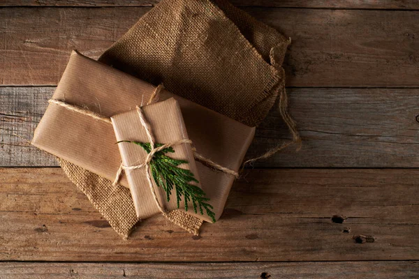 Christmas packages wrapped in kraft paper tied with jute with rustic wood background