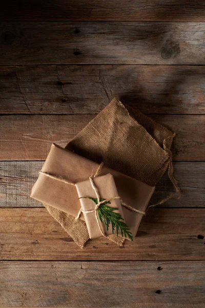 Christmas packages wrapped in kraft paper tied with jute with rustic wood background