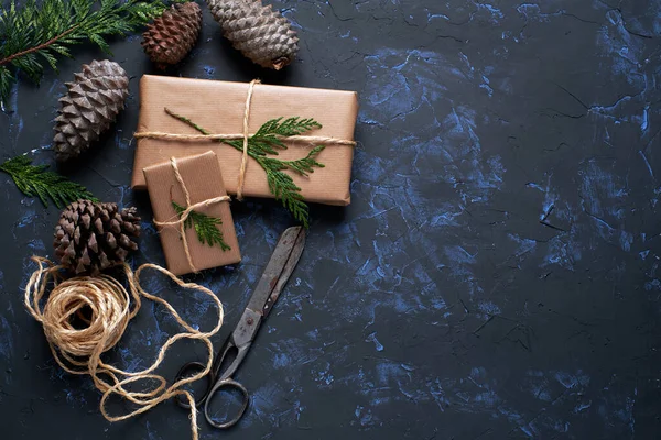 Christmas packages wrapped in kraft paper tied with jute with dark textured background
