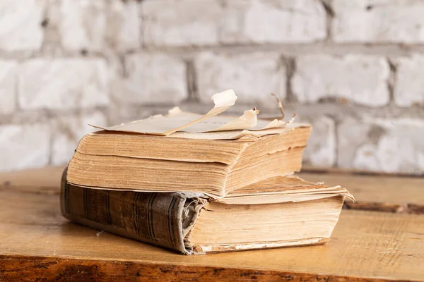 Dayak yemiş iki eski kitap hafif tuğladan yapılmış bir duvara yaslanmış..