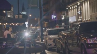 Gece şehri, geçen arabaların arka planında. İnsanlar geceleri şehirde dolaşıyorlar. Şehir hayatı. Yavaş çekim