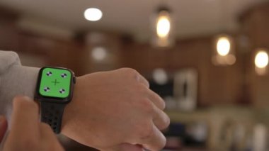 Bir adam yeşil ekranda krom anahtarı olan akıllı bir saat kullanır. Bir adamın bileğindeki akıllı bir saat. 4K içeriğini izlemek veya görüntülemek için bir düzenName