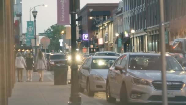 Abendstadt vor dem Hintergrund vorbeifahrender Autos und spazierender Menschen. Die Menschen laufen durch die Abendstadt. Stadtleben. Zeitlupe — Stockvideo