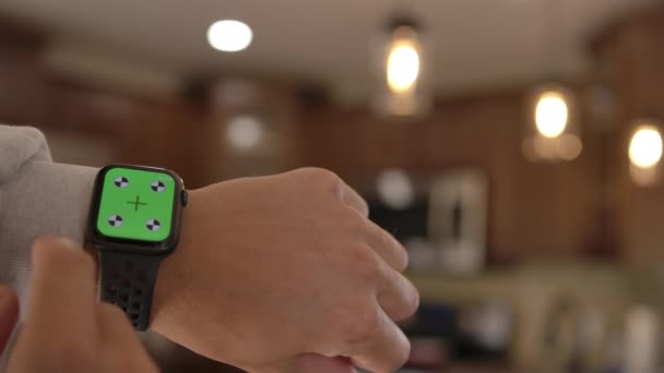 Un homme utilise une montre intelligente avec un chromatique sur un écran vert. Une montre intelligente au poignet d'un homme. Une mise en page pour le suivi ou la visualisation du contenu en 4K — Video