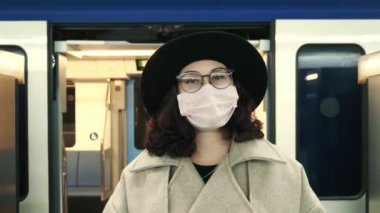 Covid-19 Coronavirus salgınından dolayı karantina sırasında boş bir metro istasyonunda tek başına duran koruyucu kıyafetli çekici bir genç kadının portresi..