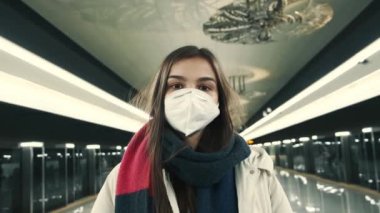 Coronavirus 'a karşı koruyucu bir maske takmış genç ve çekici bir kızın portresi. Karantina sırasında boş bir metro istasyonunda dikiliyor.