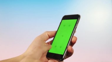Yeşilli bir ekrandaki adam telefonuyla parlak bir arkaplan kullanıyor, dikey yönelimli geçiş yapıyor. Ekrana vurur.