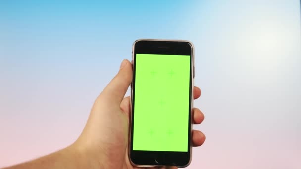 CHROMAKEY em um cara VERDE SCREEN usa seu telefone em um fundo brilhante, orientação vertical faz um deslize. — Vídeo de Stock