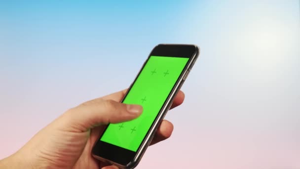 CHROMAKEY ON A GREEN SCREEN guy utiliza su teléfono sobre un fondo brillante, orientación vertical hace un golpe. Pulsa la pantalla. — Vídeos de Stock