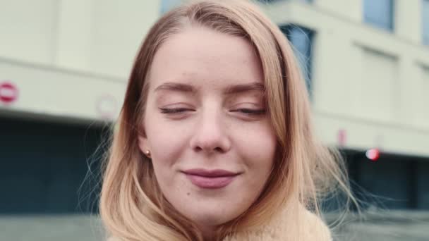 Das Gesicht eines jungen Mädchens mit weißem Haar, mit leuchtend blauen Augen, die in die Kamera schauen, lächelnd, auf den Straßen der Stadt stehend, Porträt einer schönen Dame — Stockvideo