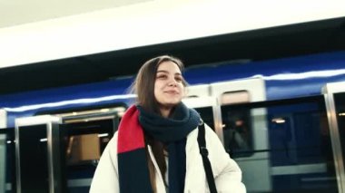 Genç, siyah saçlı bir hippi kız metro istasyonunda beklerken geçen bir trene bakıyor..