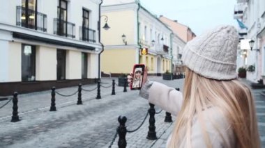 Bir kız telefonunu kullanarak sokakta video kaydediyor. Bir kız sokakta bir video kaydediyor. Sosyal medya için video hazırlama. 