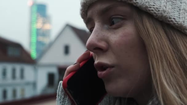 Krásná bělovlasá dívka mluví po telefonu s přáteli, šťastný, na ulici zblízka. Studentka dělá on-line objednávky na její smartphone na ulici, spokojený — Stock video
