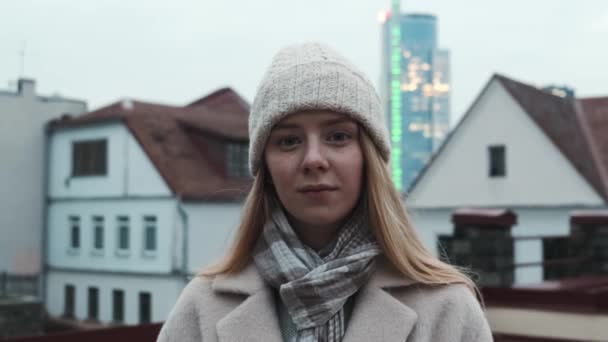 Крупный план плавного наезда на девушку с белыми волосами в шляпе на фоне города, замедленная съемка. — стоковое видео