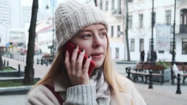 Şapkalı ve atkılı güzel bir kız şehir merkezinde yürüyor ve telefonda konuşuyor. Kız ışıklarla süslenmiş şehre hayran.. 